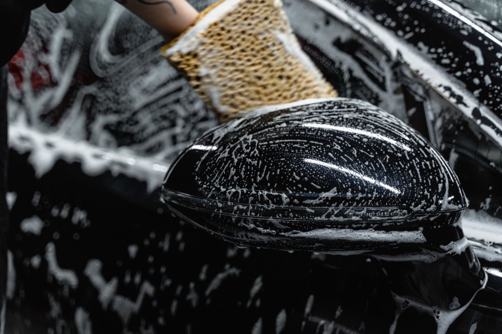 Detailer scrubbing a car mirror with soap
